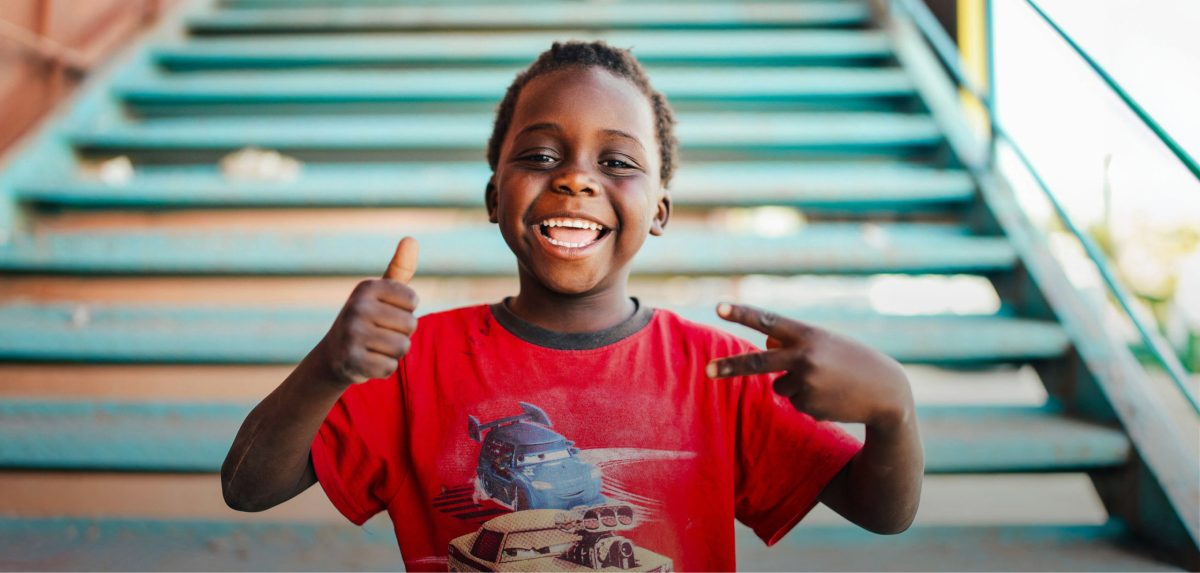 Boy with thumbs up at the bottom of the stairs